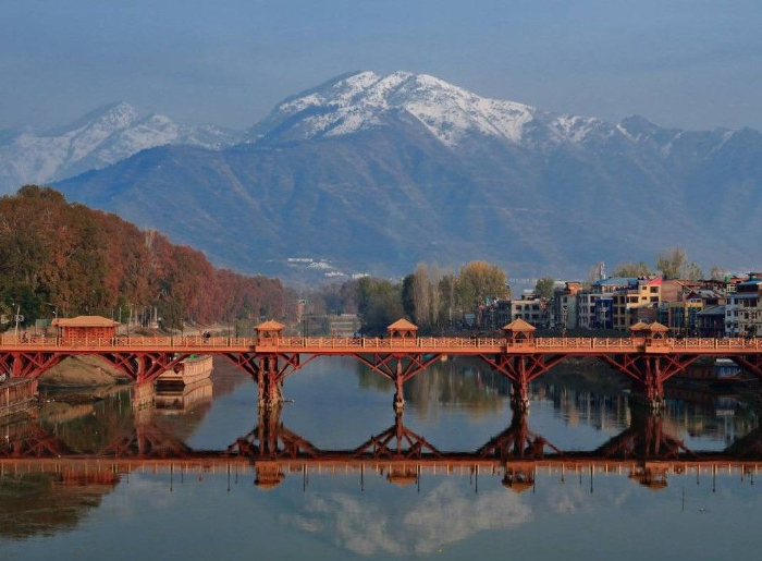 Scenic Kashmir landscape with snow-capped mountains, green valleys, and a lake on a 7-day Kashmir itinerary.