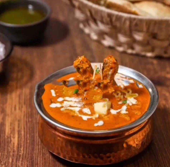 A bowl of butter chicken in creamy, buttery tomato gravy and chicken pieces