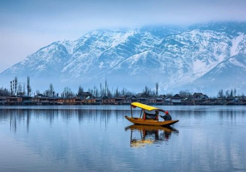 Scenic Kashmir landscape with snow-capped mountains, green valleys, and a lake on a 7-day Kashmir itinerary.